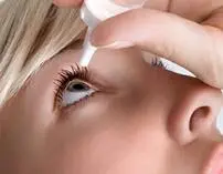 Applying eye drops to the right eye.